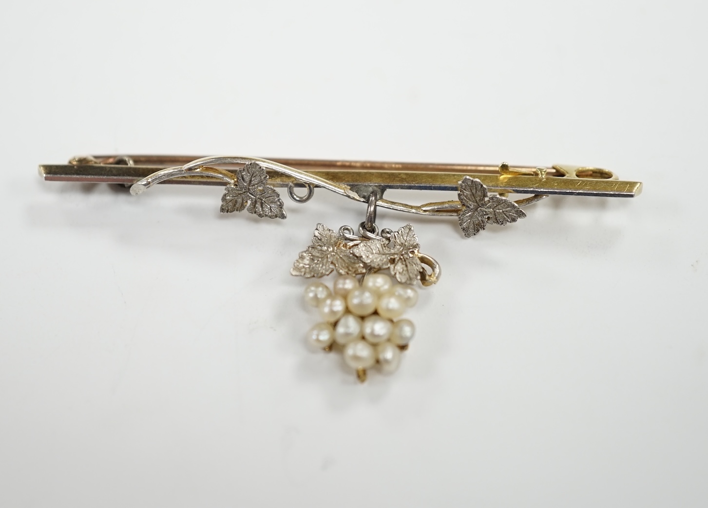 An Edwardian 15ct, platinum, and seed pearl set drop 'bunch of grapes' bar brooch, 58mm, gross weight 5.7 grams.